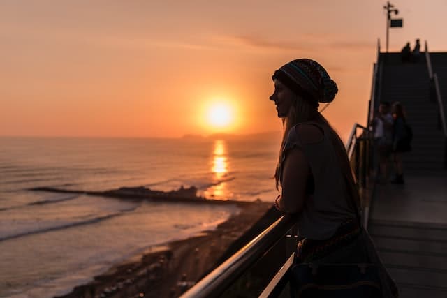 smiling woman in knit cap standing near a stairway during sunset